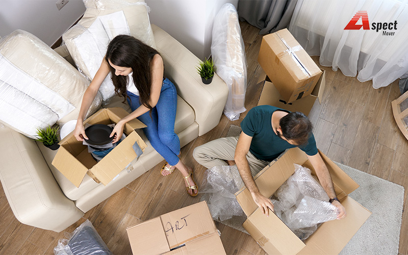 Couple unpacking moving boxes in their HDB or condo.