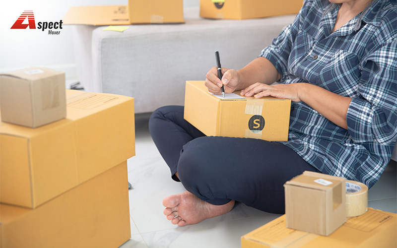Person labeling moving boxes for HDB or condo storage.